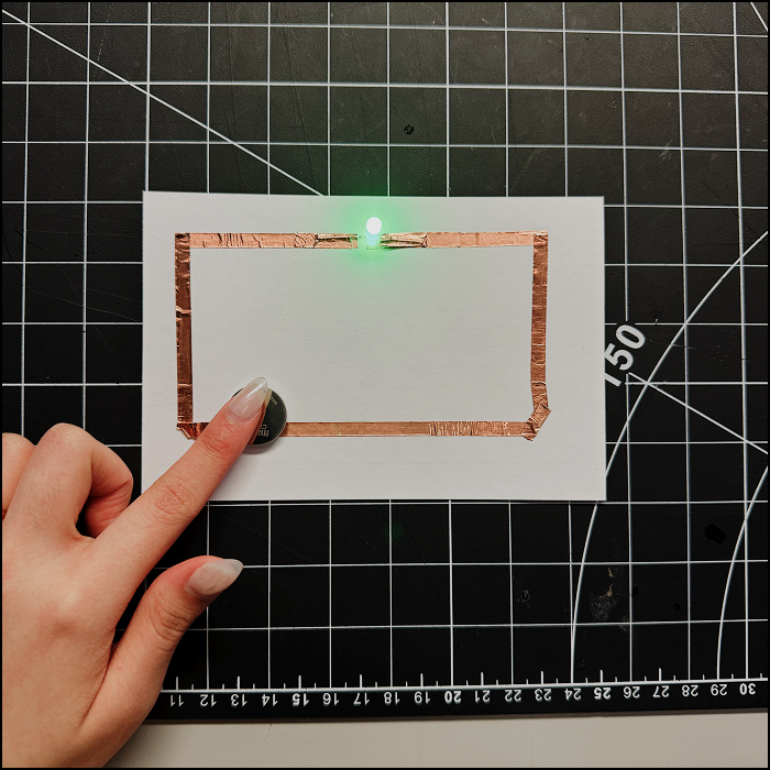 Image shows first succesfull attempt to make a simple circuit with only 1 light, activated by pressing the positive side (coppeer tape) to the battery.