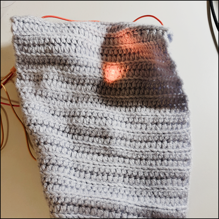 Working simple circuit hidden underneatht the crochet fabric material front view