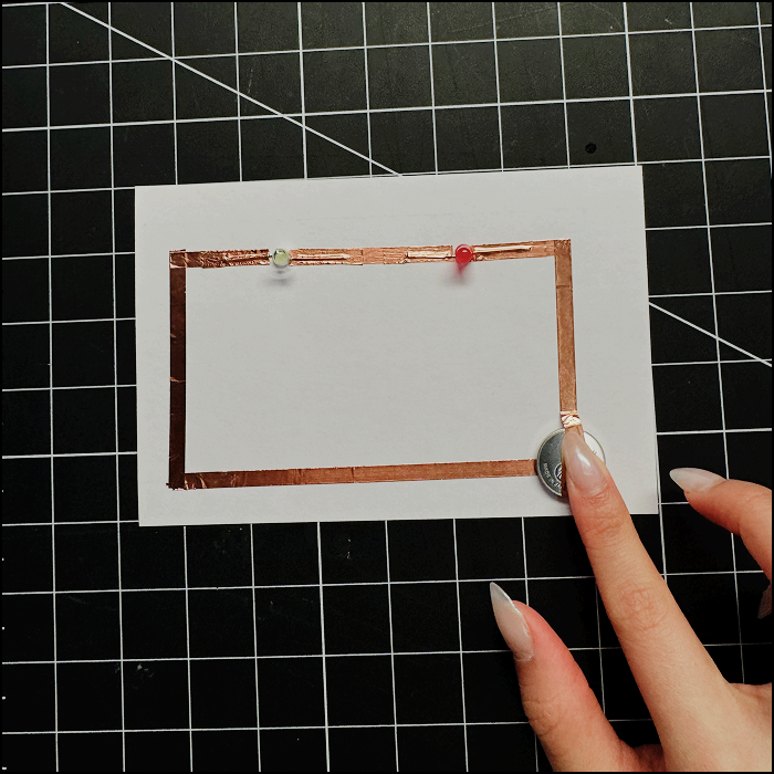 Image shows the series circuit attempt with 2 lights without the positive side of the current (copper tape) pressed on the battery, however the circuit is not lighting up