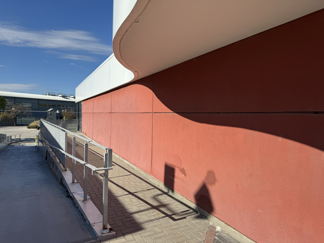 This is the red wall outside the J building on the outside corridor connected to the main building. The large space procides an interesting surface students often pass by to create something interactive.